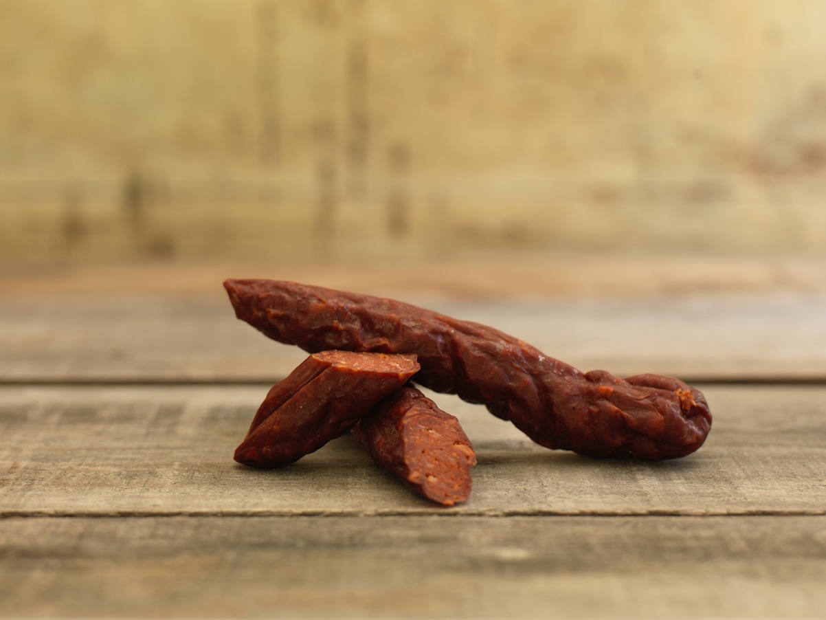 Chorizo salami with sliced pieces on a wooden surface
