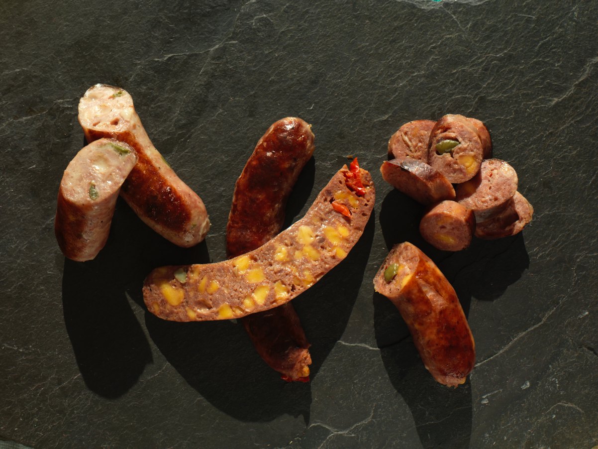 Whole and sliced jalapeno and cheddar smokies on dark slate