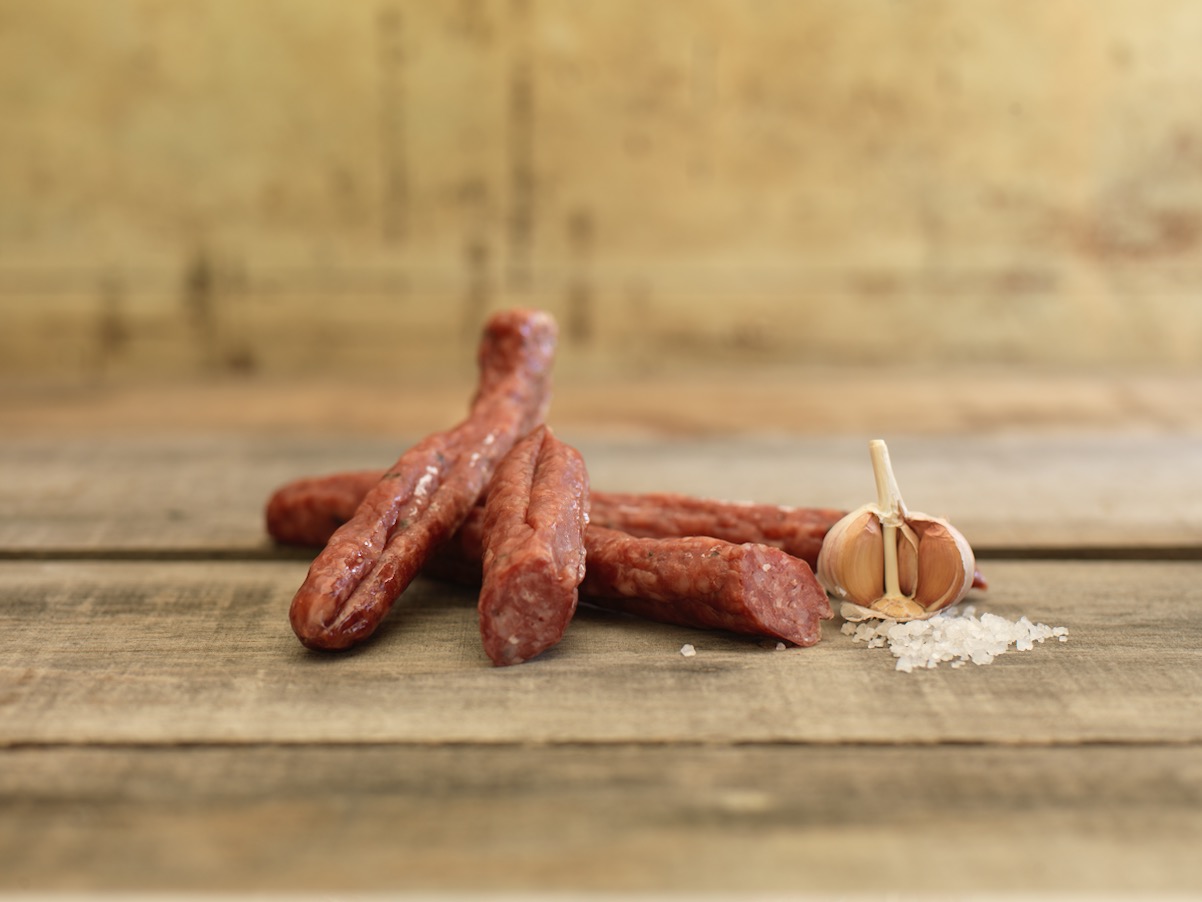 Saucisson Sec salami with sliced pieces on a wooden surface